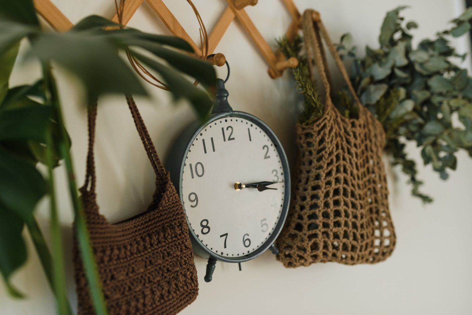 an analogue clock hanging between crocheted bags